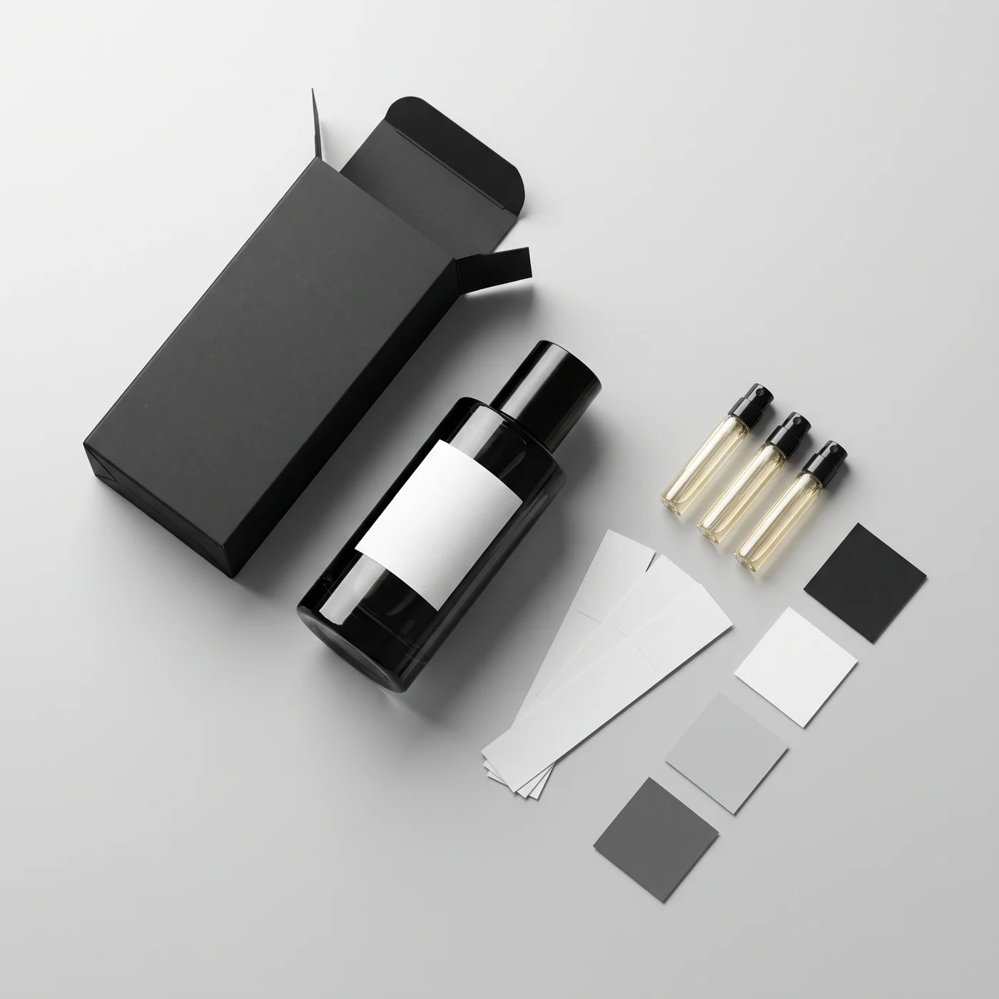 Black perfume bottle with a white label, open black folding box, three sample vials, label strips and colour swatches on a light grey surface